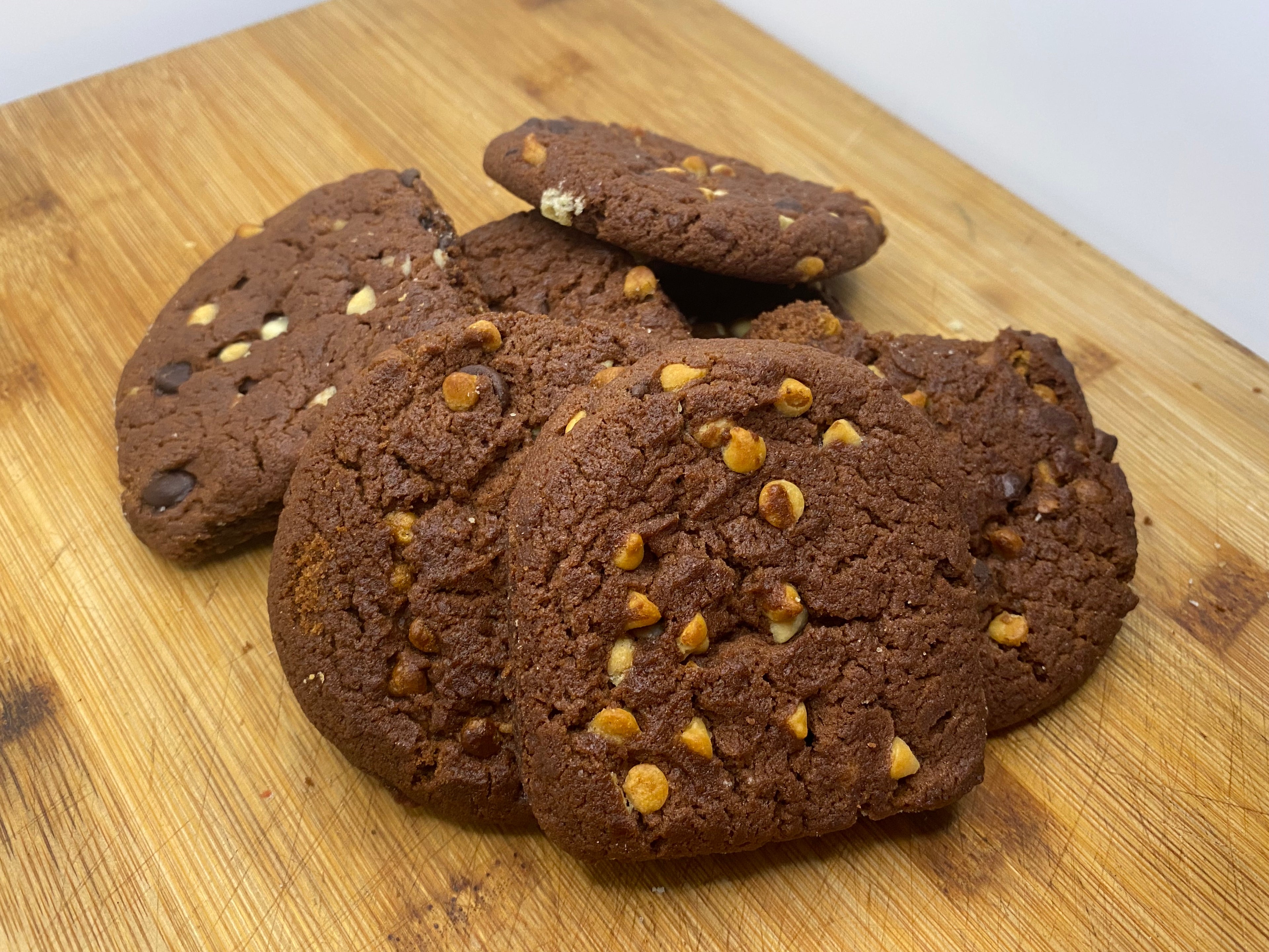 Chocolate cookies with choc chips on a wooden cutting board